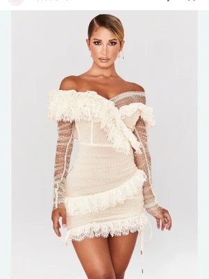 Vit offshoulder spetsklänning med volang - Supersnygg kort vit klänning med offshoulder. Klänningen har spetsdetaljer. Perfekt till student eller sommarfest! Figurnära passform och unik design. Jag har använt klänningen 1 gång på studenten under frukosten och utspringet så den är i nyskick. Jag är xs/s och den passar väldigt bra på mig.