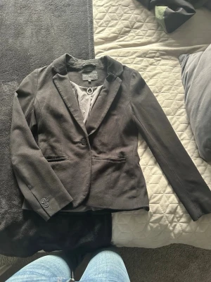 Svart kavaj från Stockh LM - Snygg svart kavaj från Stockh LM i klassisk modell med en knapp framtill och två fickor. Kavajen har smal passform och är tillverkad i ett mjukt material som känns bekvämt. Perfekt för att lyfta din outfit med en stilren look.