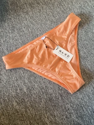 Persikofärgade bikinitrosor - Orangea/persikofärgade skimriga bikinitrosof från NA-KD! Aldrig använda, lite små i storleken skulle jag säga.