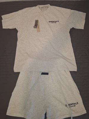 En grå Essentials set  - Säljer en grå Essentials set på grund av att den är liten och inte passar mig. Perfekt till dig som vill ha en fin sett till sommaren. Dom är inte används alls dom är sprillans nya.
