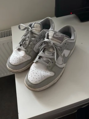 Nike Dunk Low grå och vita sneakers - Nike Dunk Low sneakers i grått och vitt. Jag har använt dem ett antal gånger men fortfarande i ett bra skick