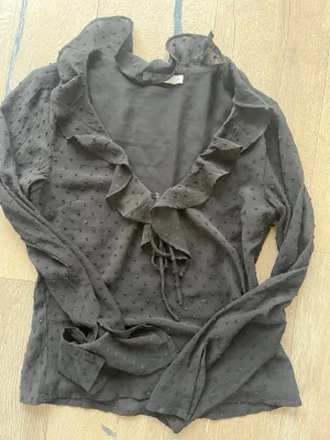 Svart blus med volang från NA-KD - Svart blus från NA-KD med långa armar som har en slits vid händerna. Det finns även en seem less  dragkedja i sidan. Passar för lite finare tillfällen/fest<3