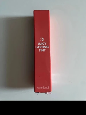Rom&nd Juicy Lasting Tint Litchi Coral - Juicy Lasting Tint från Rom&nd i färgen 09 Litchi Coral. Ett läppstift med glossig finish i en fräsch korallnyans. Förpackningen är smal och stilren i plast med tydlig märkning. Perfekt för dig som vill ha färg och glans i ett.