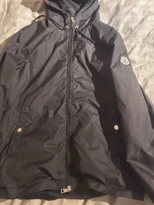 Moncler windbreaker  - Fin Vindjacka, inga hål eller liknande. Storlek 2=M passar mig bra som är 176. Nfc Scan funkar och industritags finns. Två taggar på zipen har gått sönder men det går fortfarande att dra upp hela vägen