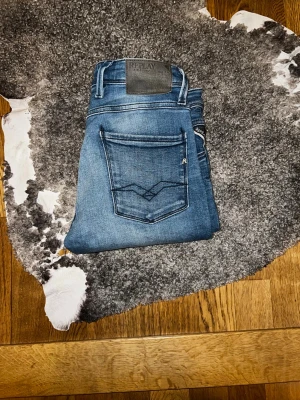 Blå Replay jeans med smal passform - Säljer ett par blå jeans från Replay anbass med smal passform och klassisk femficksdesign. Jeansen har snygga slitningar och Replay-logga på fickan. Tillverkade i stretchigt denimtyg för extra komfort. Riktig schyssta! Skirv vid funderingar! 