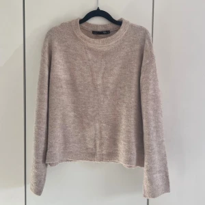 Beige stickad tröja  - Mysig beige stickad tröja från lager 157 med rund halsringning och avslappnad passform. Tröjan har långa ärmar och ribbade muddar vid hals, ärmslut och nederkant. Perfekt för lager på lager och enkel att matcha till olika outfits.