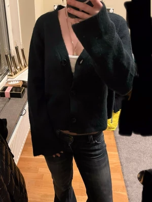 Marinblå kofta - Mysig marinblå kofta med croppad passform och stora knappar framtill. Koftan har v-ringad halsringning och långa ärmar med lite lösare passform. Perfekt att slänga över ett linne eller t-shirt för en chill look.