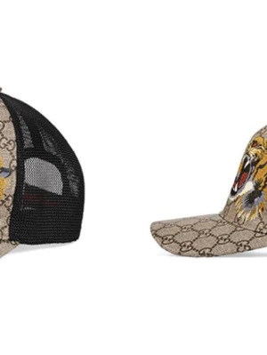 Gucci keps med tigertryck - Säljer en snygg Gucci keps med klassiskt GG-mönster i beige och brunt, prydd med två tigrar framtill. Kepsen har svart mesh på sidorna och justerbar rem bak. Perfekt för dig som vill sticka ut med en exklusiv accessoar. 