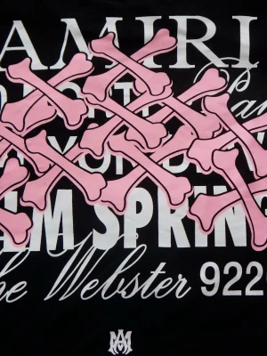 Designer | Tshirt med print  - Säljer en svart t-shirt med stort tryck på ryggen. T-shirten har vita texter och ett grafiskt motiv med rosa korslagda ben. Oversized fit och klassisk rund hals. Perfekt statement-plagg för dig som gillar streetwear. Perfekt för sommaren! 