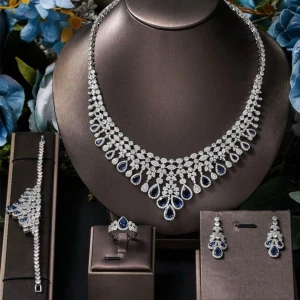 Silverfärgat halsband med blå stenar - Ett riktigt statement-halsband i silverfärg med gnistrande klara stenar och droppformade blå detaljer. Halsbandet har en elegant och lyxig design med flera lager av små stenar som ger en exklusiv känsla. Perfekt för dig som vill sticka ut och addera glamour till din look. Lyxig smyckeskrin  medföljer.