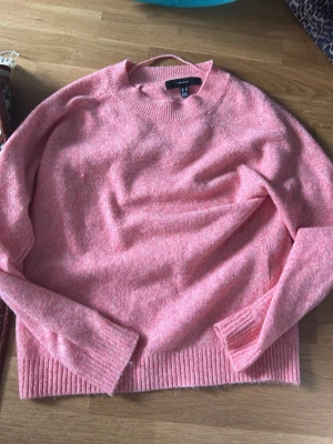 Rosa stickad tröja från Vero Moda - Mysig rosa stickad tröja från Vero Moda med rund halsringning och ribbade muddar vid ärmslut och nederkant. Perfekt för lager på lager och enkel att matcha till jeans eller kjol. Materialet känns mjukt och behagligt mot huden.