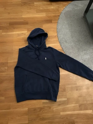 Marinblå hoodie från Polo Ralph Lauren - Snygg marinblå hoodie från Polo Ralph lauren! 10/10 skick man ser inga tecken på att den är använd! Nästan helt ny knappt använd köpt på zalando. 