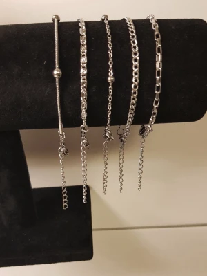 Set med fem silverfärgade armband - Fem stilrena armband i silverfärgad metall med olika kedjedesigner. Ett armband har små pärldetaljer, medan de andra har olika länkar och minimalistiska detaljer. Perfekta att mixa och matcha för en trendig look. Rostfritt! 
