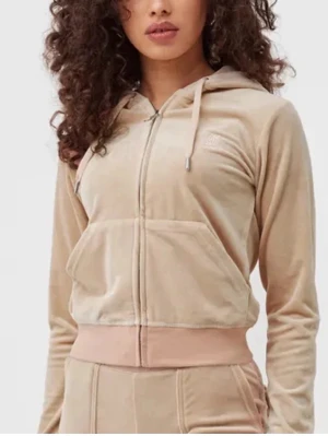 Beige velourset från Juicy Couture - Säljer ett beige velourset från Juicy Couture med zip hoodie och matchande byxor. Hoodien har ficka framtill, dragsko i huvan och ribbade muddar. Byxorna har raka ben och fickor bak med knappdetalj.pris går att diskutera 