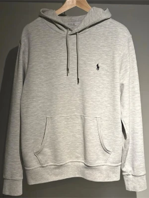 Ljusgrå hoodie från Polo Ralph Lauren - Snygg ljusgrå hoodie från Polo Ralph Lauren med klassisk huva och dragsnören. Passar någorlunda bra på mig och jag är 185cm, Nypris:1800 mitt pris: 950kr✅ Den är lite nopprig också så ni vet. Annars skick 8/10
