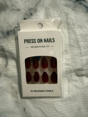 Mörkröda press-on naglar, 24-pack - Snygga mörkröda press-on naglar i mandelform. Förpackningen innehåller 24 återanvändbara naglar som är enkla att applicera på bara en minut. Perfekt för dig som vill fixa naglarna snabbt och smidigt hemma.