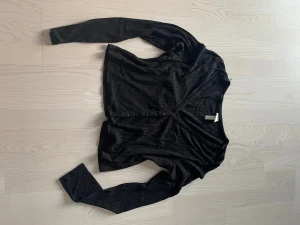 Tröja - Svart tröja / kofta som har knappar längs modellen. Stretchigt material