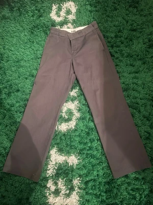 Mörkgrå Dickies 873 chinos - Säljer ett par mörkgrå Dickies 873 chinos med rak passform och klassisk look. Byxorna har sidofickor och är tillverkade i ett slitstarkt bomullsmaterial. Perfekta för dig som gillar streetwear och enkel stil.
