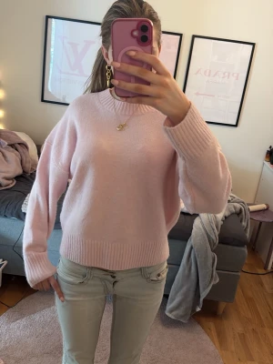 Ljusrosa stickad tröja från Zara - Supersöt ljusrosa stickad tröja från Zara med rund halsringning och breda ribbade muddar vid ärmslut och nederkant. Tröjan har en avslappnad passform och är perfekt för att skapa en mysig och trendig look.