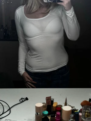 Vit långärmad topp - Vit långärmad topp med rundad halsringning och långärmad. Toppen är figurnära och lite genomskinlig. Från Lager 157 i storlek M