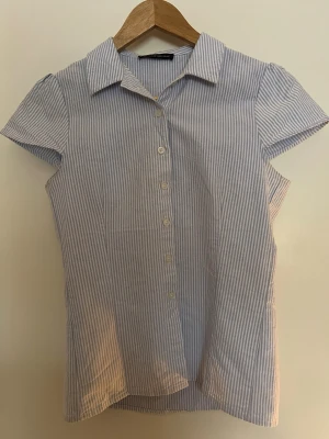 Blårandig kortärmad skjorta - Kort ärmad blå randig skjorta från Brandy Melville. Med knappar fram. Storlek xs/s. 💕