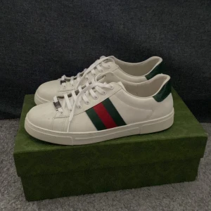 Cucci ACE sneaker  - Säljer ett par klassiska vita sneakers från Gucci med den ikoniska röd-gröna randen på sidan. Cucci ACE sneaker använt några gånger i o med all snö så perfekta nu på våren. Du får me box-snören-bag o allt sånt. Nypris ligger runt 7-8 tusen. Skriv om du vill disk pris