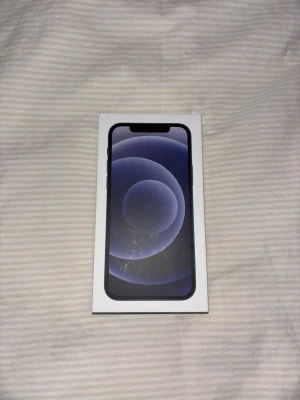 Svart iPhone 12 med originalkartong - Säljer en svart iPhone 12 från Apple. Telefonen har en stilren design med platt framsida och rundade kanter. Levereras i originalkartong. Skärmen är i glas och ramen är av aluminium. Perfekt för dig som vill ha en modern och snygg smartphone. Jag kan tänka mig att gå ner i pris om affären går fort!!