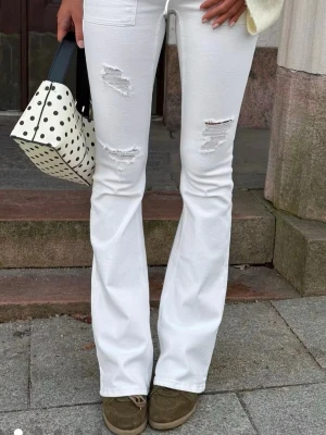 Vita bootcut jeans med knyt - Säljer ett par vita bootcut jeans med knyt där fram. Storlek Xs och sitter jättebra på mig som är 163 cm med långa ben. Kan skicka exakta mått om det skulle behövas. Använda 3 gånger så inga tydliga tecken på användning. Kan posta nästan varje dag