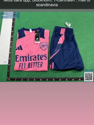 Arsenal träningsset rosa/blå Adidas - Snyggt Arsenal träningsset från Adidas i rosa och marinblått. Setet består av ett linne med tryckt Arsenal-logga och sponsor, samt matchande shorts med rosa detaljer. Perfekt för fotbollsträning eller gymmet. Materialet är lätt och andas.  OBS!!! MÖTS BARA UPP, T-CENTRALEN , MALL OF SCANDINAVIA 