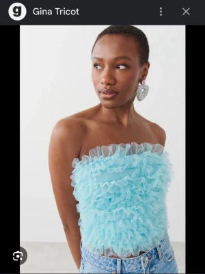 Blå volang tubtopp från Gina Tricot - Supersöt blå tubtopp från Gina Tricot med massor av volanger över hela toppen. Axelbandslös bandeau-modell som ger en trendig och lekfull vibe. Perfekt att styla med jeans eller kjol för en cool look 🦋🩵 Aldrig använd! 