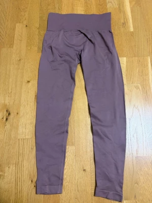 Lila sömlösa leggings med hög midja - Snygga lila leggings med hög ribbad midja och sömlös design. Stretchigt material som sitter skönt och formar sig efter kroppen. Perfekta för träning eller chill. Inga synliga loggor eller märken.