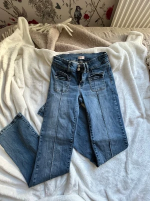 Blå jeans från Nelly  - Superfina blåa jeans från Nelly. Jeansen har dubbla knappar i midjan och två stora fickor framtill. Perfekta för en trendig och avslappnad stil.