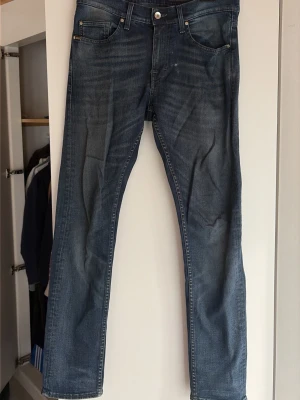 Blå straight fit tiger of sweden jeans med slitningar - Säljer ett par blå tiger of sweden jeans med straight fit och snygga slitningar. Klassisk femficksdesign och knappstängning framtill. Jeansen har en cool tvättad look och är gjorda i denim. Perfekta för dig som gillar en avslappnad stil.