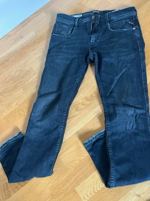 Mörkblå jeans från Replay - Snygga mörkblå jeans från Replay med klassisk femficksdesign och raka ben. Jeansen har diskreta slitningar och kontrastsömmar. Perfekta för en avslappnad och trendig look. 28/32 anbass