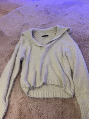 Ljusbeige stickad tröja Gina Tricot - Mysig ljusbeige stickad tröja från Gina Tricot med krage och v-ringning. Tröjan har långa ärmar och ribbade muddar vid ärmslut och nederkant. Perfekt för lager på lager vardagsstil.