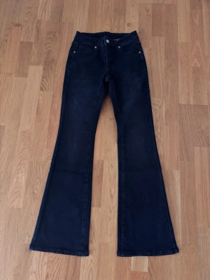 Svarta bootcut jeans - Säljer ett par helt nya svarta jeans med utsvängda ben. Lappen kvar. Passar inte mig. Storlek xs/34. Jättefina och stretchigt och skönt material. Inga defekter alls! Midja: 33cm Midjehöjden 21,5cm Innerbenslängden 79cm Ytterbenslängden 106cm