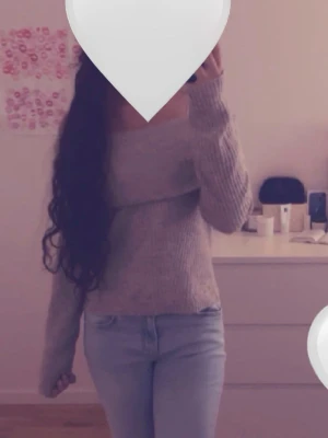 Beige/grå off shoulder stickad tröja - Trendig beige stickad tröja med off shoulder-design och bred krage. Tröjan är ribbstickad och har långa ärmar. Perfekt för dig som vill ha en stilren och mysig look. Materialet känns mjukt och följsamt.