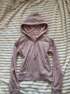 Rosa hoodie med dragkedja Hollister - En rosa hoodie med dragkedja ifrån Hollister i storlek S! Defekter som läsa trådar, urtvättad kan förekomma och ett litet håll vid ärmen, syns på bild❣️