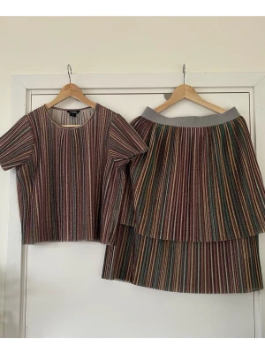 Monki - glittrigt randigt set med topp och kjol - storlek S / M - Färgglatt glittrigt randigt set med plisserad topp och kjol från Monki. Storlek S på toppen och storlek M på kjolen. Fin modell med korta ärmar och rund halsringning. Kjolen är i två lager med bekväm resår i midjan för bästa passform. Mycket gott skick!