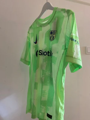 Barcelona matchtröja Lamine Yamal #19 - Snygg Barcelona matchtröja i neonljusgrönt med tryck Lamine Yamal och nummer 19 på ryggen. Tröjan har klubbmärke, Nike-logga och Spotify som sponsor framtill. Tillverkad i lätt och ventilerande material, perfekt för fotboll eller matchdag💚💚💚