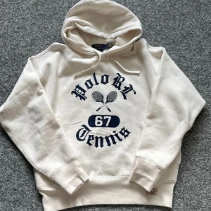 Vit hoodie Polo Ralph Lauren Tennis - Snygg vit hoodie från Polo Ralph Lauren. Använd väldigt få gånger och där med inga defekter alls. Tröjan är i storlek S men sitter lite pösigare eftersom det är en speciell modell från Ralph Lauren. 