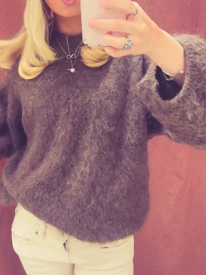 Brun fluffig stickad tröja Ame - Supermjuk och oversized stickad tröja från Ame i en snygg brun nyans. Tröjan har breda ärmar och en fluffig, cozy känsla som gör den perfekt för kyliga dagar. Passar till både jeans och kjol för en avslappnad look. Den är även one size 