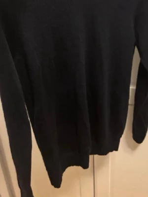 Marin blå stickad tröja från Uniqlo - En klassisk marinblå stickad tröja från Uniqlo i storlek M. Tröjan har rund halsringning, långa ärmar och ribbade muddar vid ärmslut och nederkant. Perfekt basplagg för lager-på-lager och enkel att matcha med olika outfits. Den är väldigt liten i storlek.
