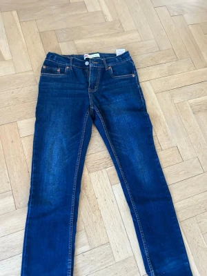 Mörkblå raka jeans från Levi's - Snygga mörkblå jeans från Levi's med klassisk femficksmodell och raka ben. Jeansen har kontrastsömmar och Levi's ikoniska bakfickor med broderad detalj. Perfekta till en avslappnad stil och tillverkade i slitstark denim.
