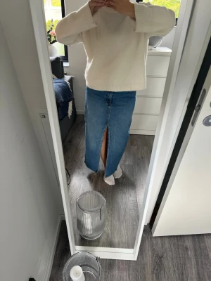 Lång jeanskjol med slits framtill - Säljer en klassisk blå lång jeanskjol med en snygg slits framtill. Kjolen har en rak passform och är tillverkad i denim, vilket gör den både stilren och enkel att matcha med olika toppar. I bra skick!