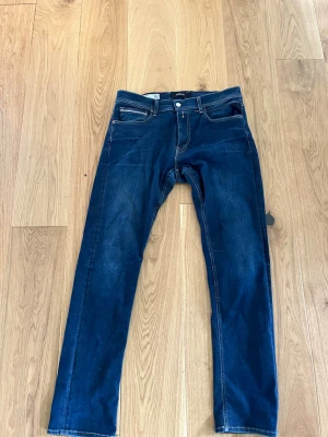 Mörkblå Replay Grover jeans - Snygga mörkblå jeans från Replay med klassisk femficksdesign och raka ben. Jeansen har kontrastsömmar och en stilren look som passar till det mesta. Materialet är denim med en lätt stretch för extra komfort