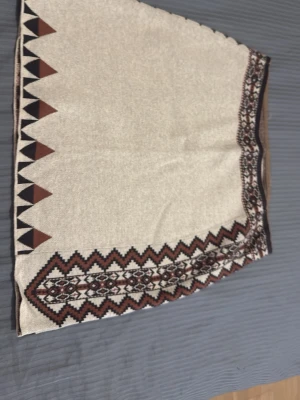 Mönstrad kjol från Odd Molly - Snygg kjol från Odd Molly med beige bas och brunt, svart och vitt geometriskt mönster längs kanterna. Kjolen är i bomull och har en kort passform med coola detaljer som ger en bohemisk vibe.