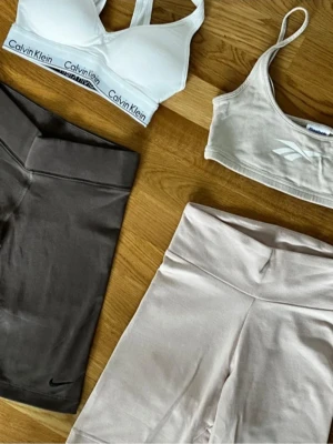 Reebok träningsset - Reebok träningsset i beige med bikershorts och matchande top i mjuk bomull. Säljs som set eller separat.