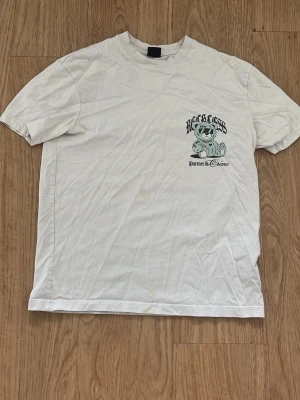 Vit t-shirt från FSBN med tryck - Vit Partner in crime t-shirt från FSBN i relaxed fit med coolt tryck på bröstet som föreställer en björn med solglasögon och texten 'Reckless'. Klassisk rund halsringning och korta ärmar. Perfekt för en avslappnad stil.