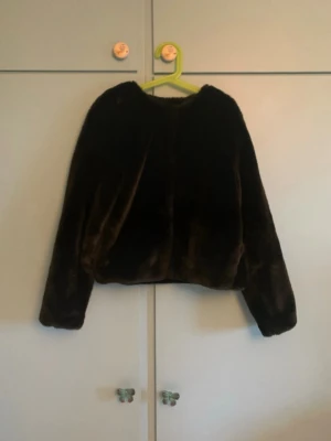 Svart mjukisjacka - Snygg svart pälsjacka/mjukisjacka med rak passform och långa ärmar. Jackan har en enkel design utan synliga detaljer och är perfekt för att hålla värmen under kalla dagar. Passar dig som vill ha en stilren och trendig look. 💗